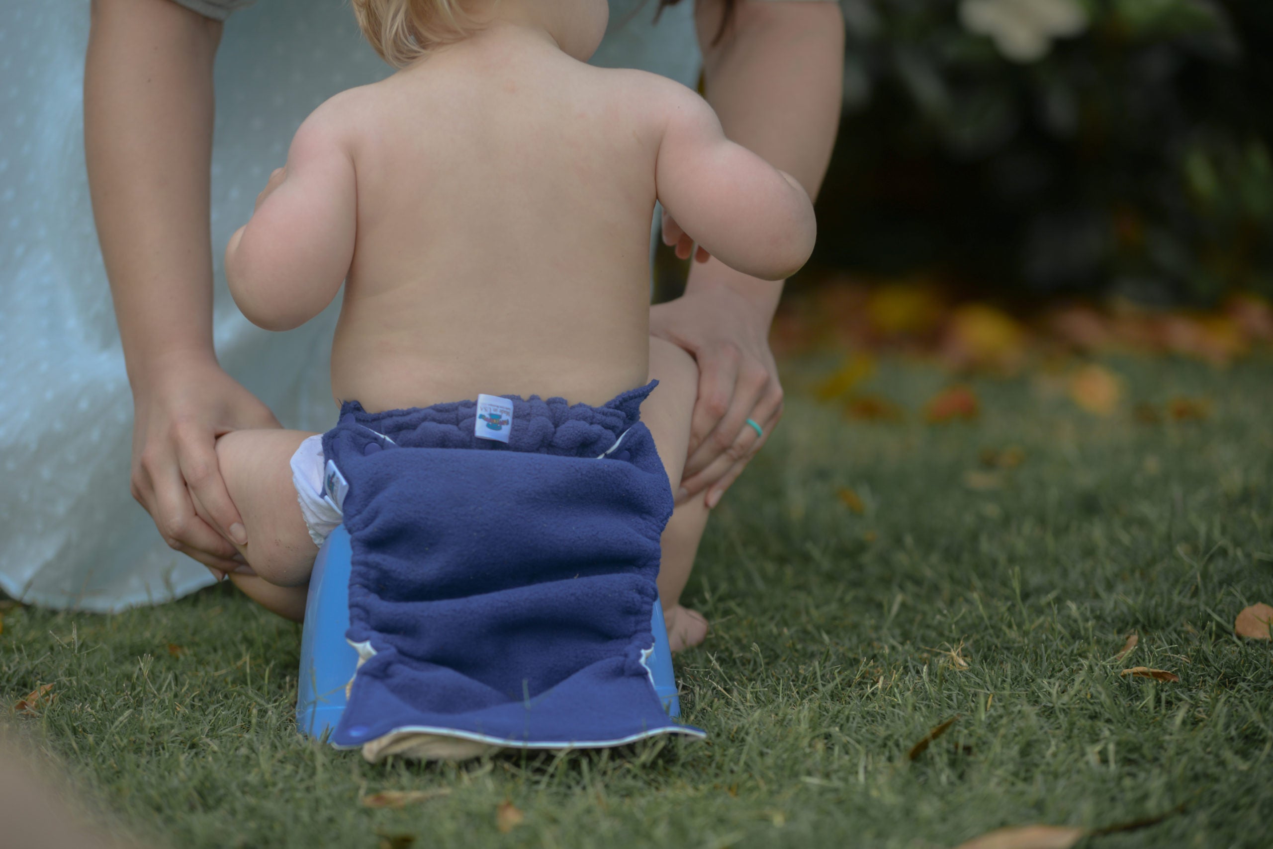 A baby uses the potty wearing a flappy-nappy diaper